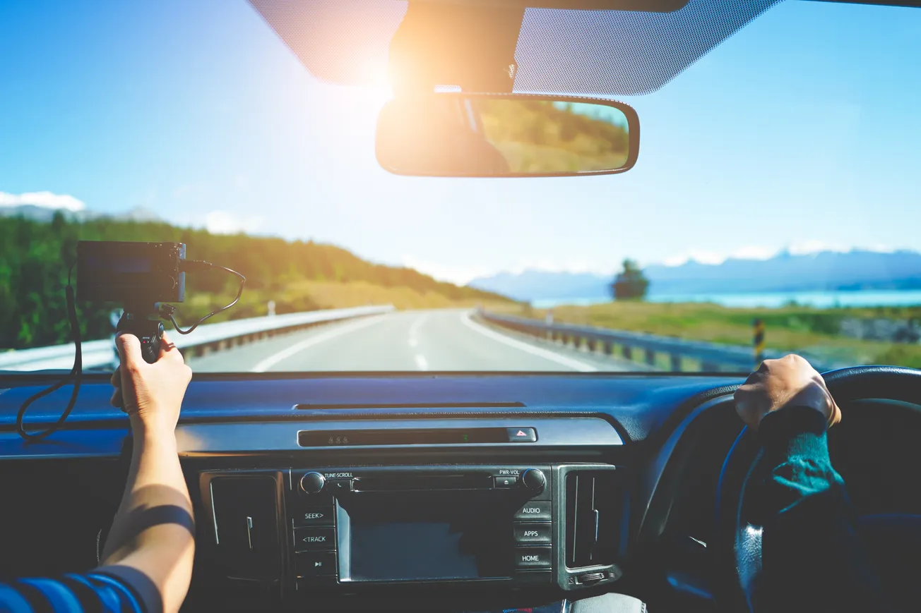Passenger filming scenic road trip through car windshield – Travel vlogging and on-the-road content creation concept.