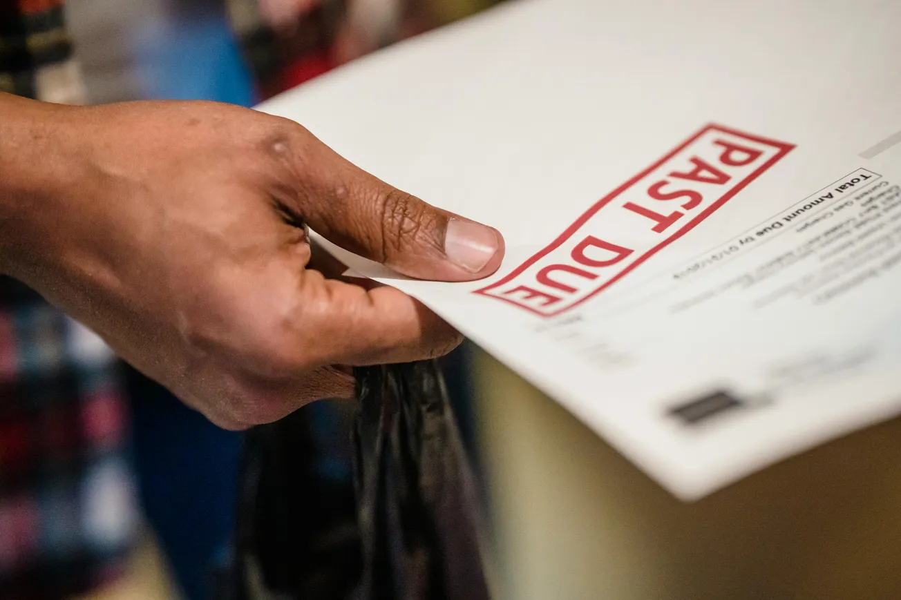 A hand holding an envelope with "PAST DUE" in bold red letters. The background is blurred, creating a sense of urgency and concern.
