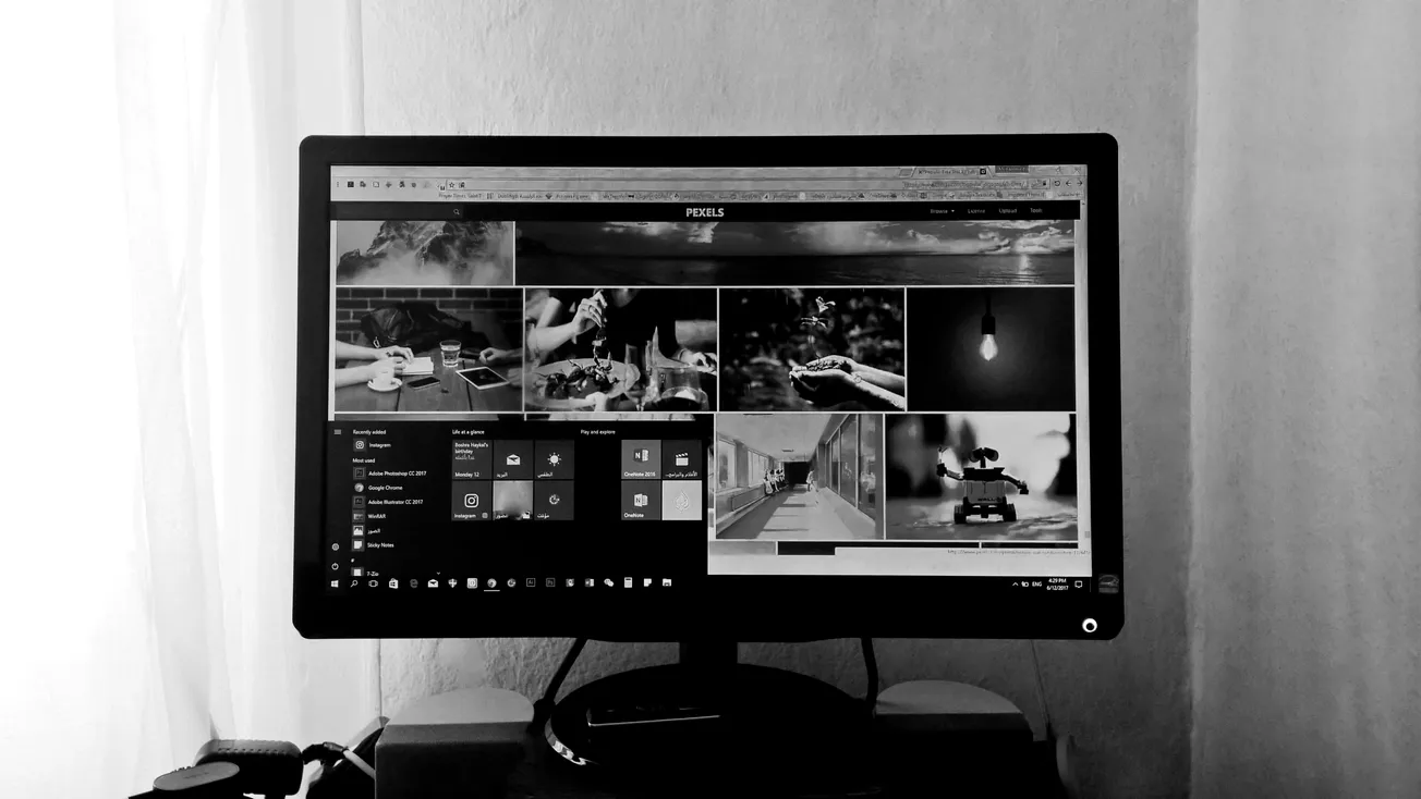 Black and white photo of a computer monitor displaying various images on a webpage. The room's soft lighting adds a calm and focused atmosphere.
