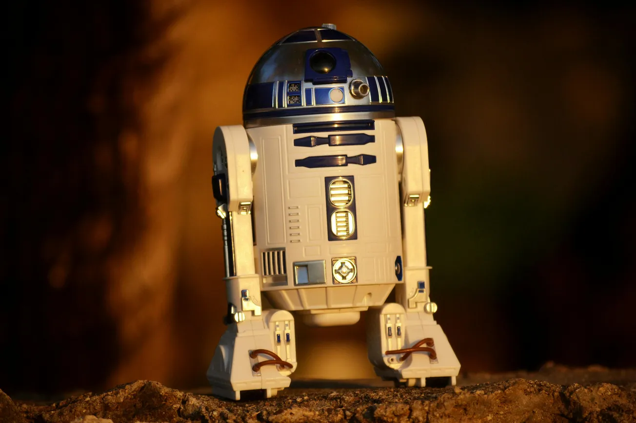 A small, detailed model of R2D2 stands on a rock. Warm lighting suggests a sunset, creating a nostalgic tone.