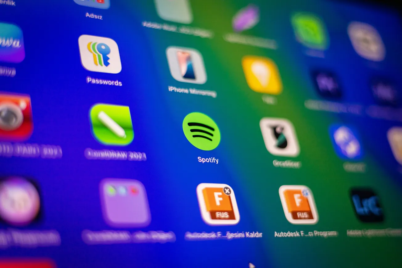Close-up of a digital screen showing colorful app icons, including Spotify, on a blurred, vibrant background, evoking a sense of modern technology.