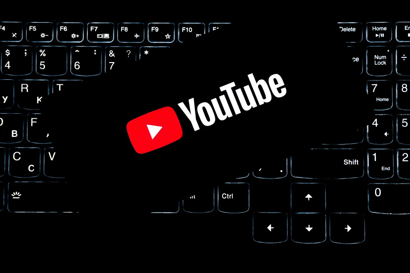 A glowing YouTube logo is centered over a dimly lit keyboard. The contrast creates a modern, tech-focused atmosphere, highlighting digital content creation.