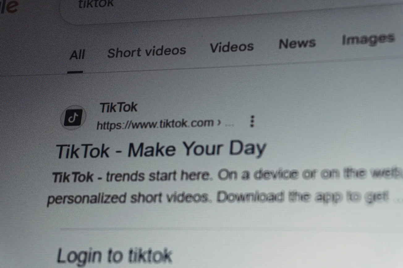 Close-up of a computer screen displaying Google search results for TikTok. The website header reads "TikTok - Make Your Day." Minimalist and informational tone.