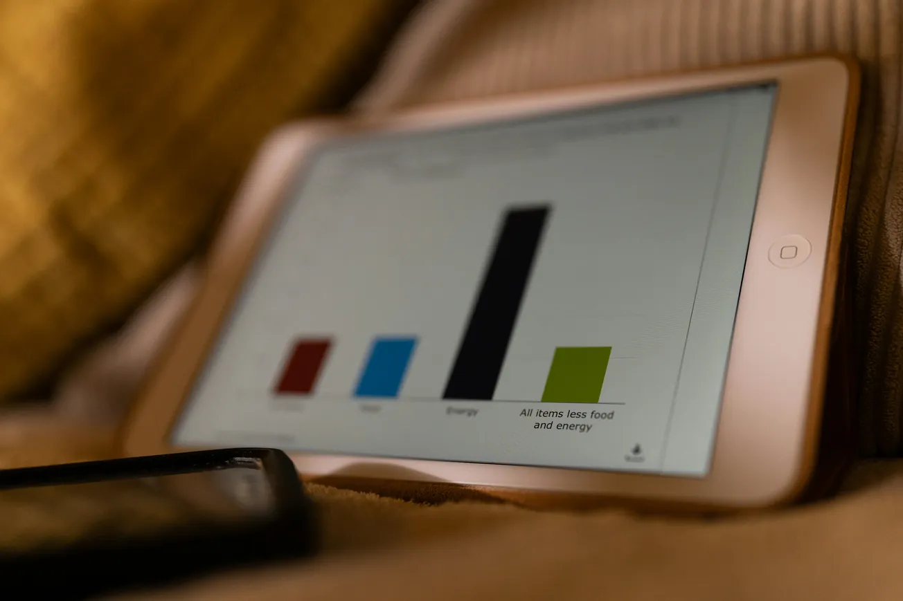 Tablet displaying a bar chart with four colored bars: red, blue, black, and green. The cozy setting suggests a relaxed atmosphere.