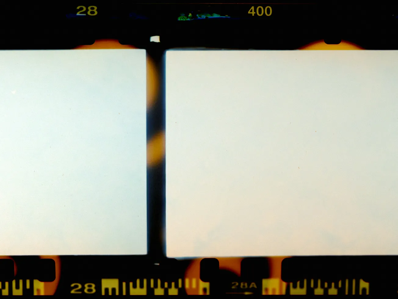 Close-up of two blank film strips with dark edges and orange light leaks. Numbers "28" and "400" visible, evoking a nostalgic, retro feel.