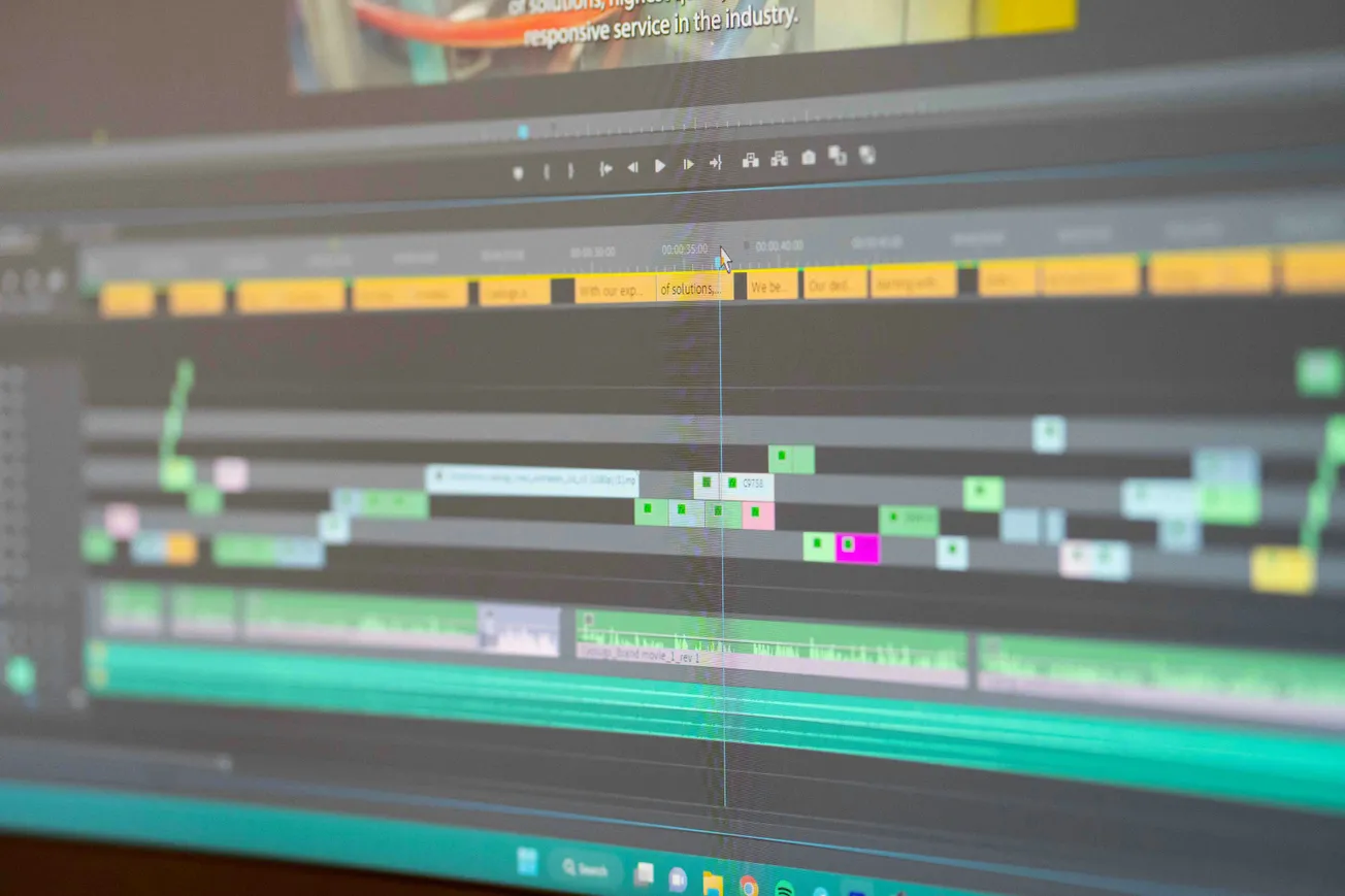 Close-up of a screen displaying video editing software, showing multicolored timelines and audio tracks. A diagonal line indicates a screen glitch.